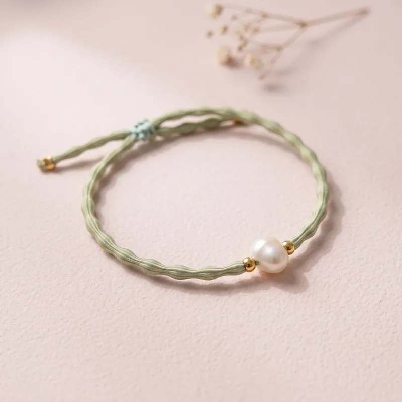 Pulsera verde con perla sobre fondo rosa